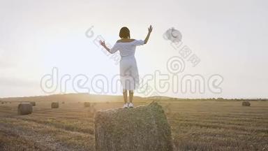 意大利托斯卡纳的一个年轻女孩，站在干草堆上，在蓝色的背景下举起和<strong>放下</strong>手臂